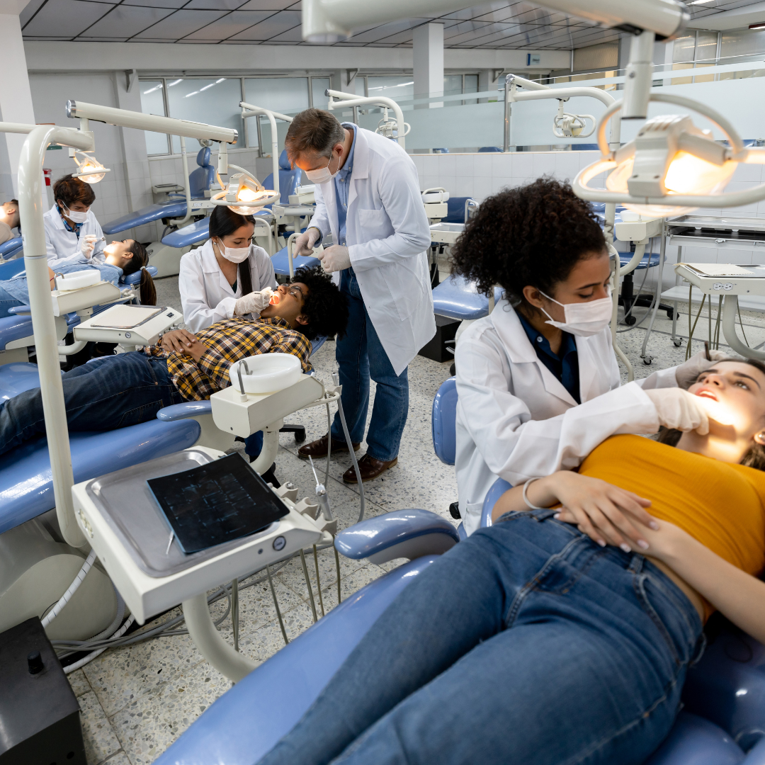 Two dental hygienists are posing for a picture in front of a flower garden.