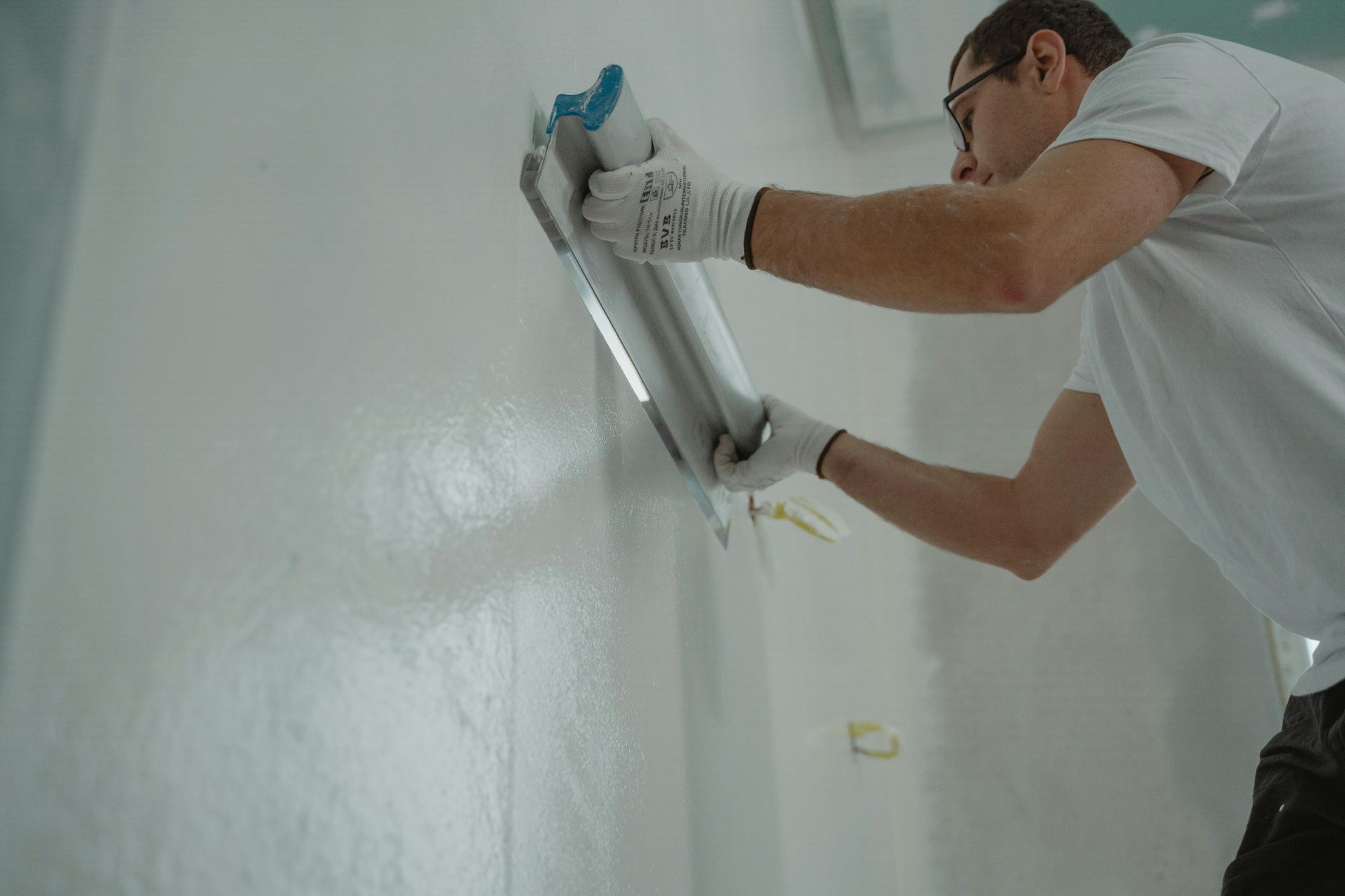 Worker installing a fluorescent light fixture on a white ceiling with a drill