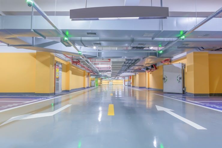 Empty underground parking garage with yellow walls, glossy floor, and directional arrows on the lane