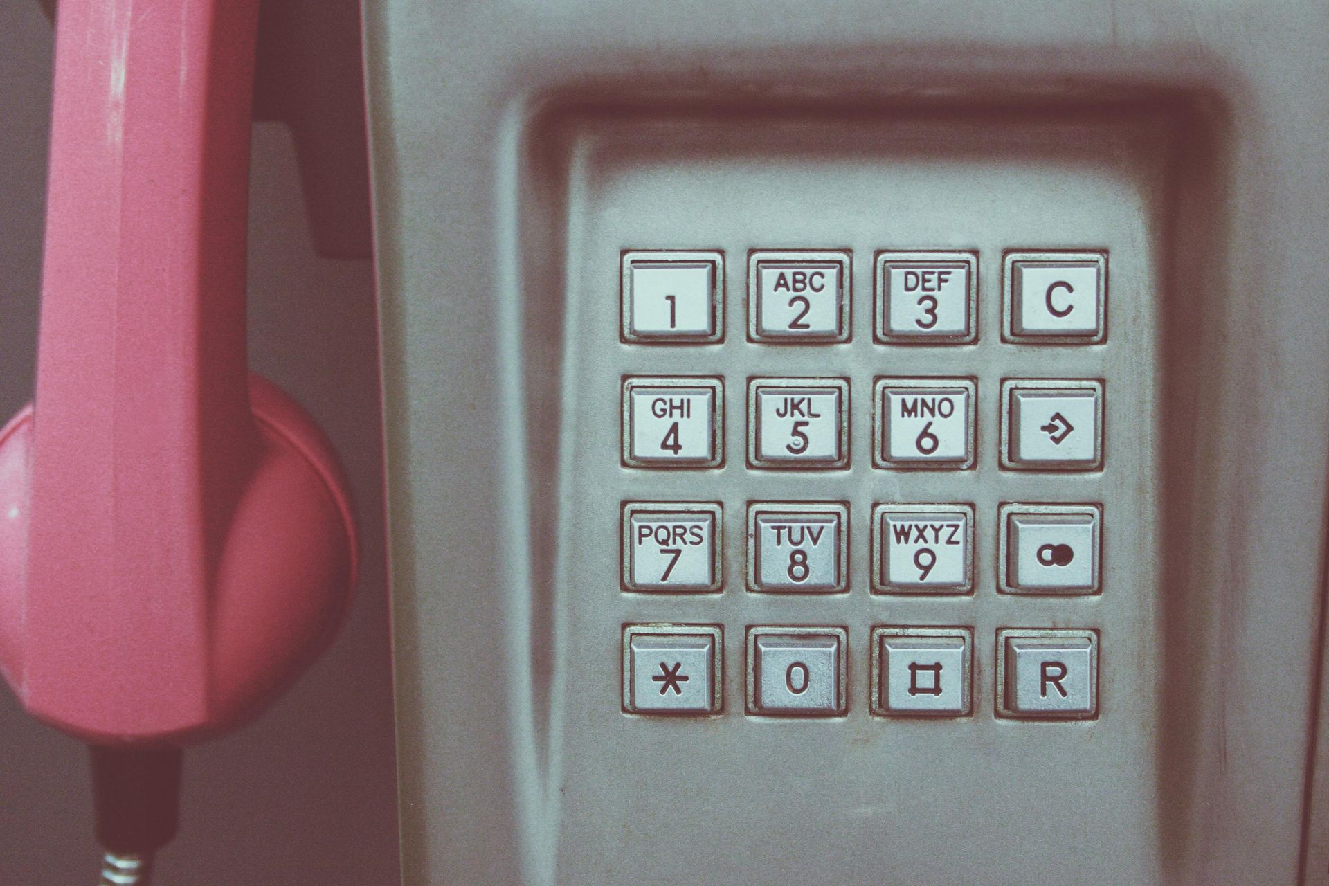 A close up of a pink telephone with a keypad