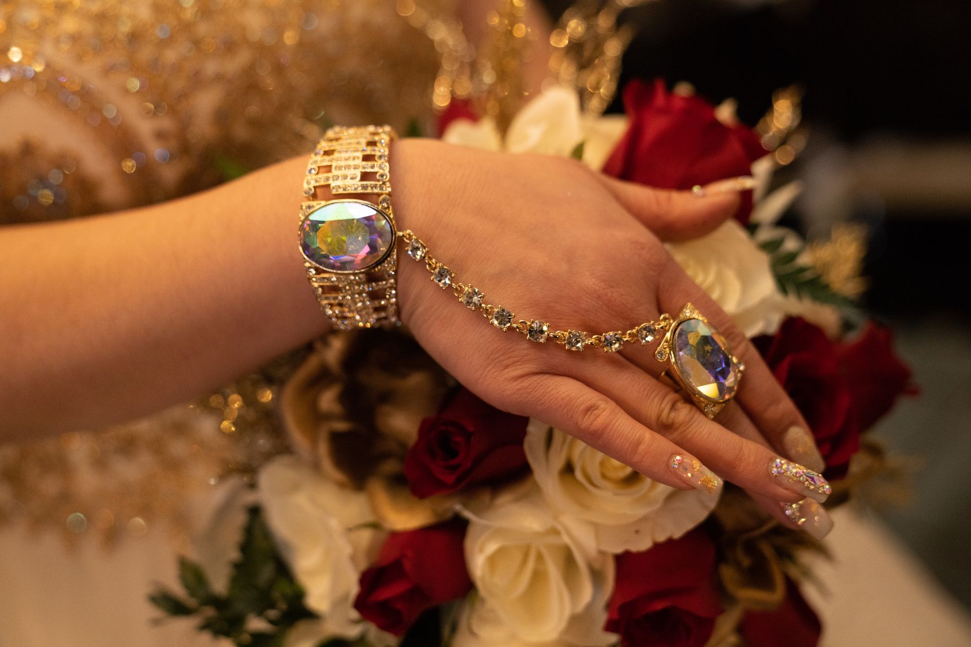 A woman wearing a bracelet and a ring is holding a bouquet of flowers.