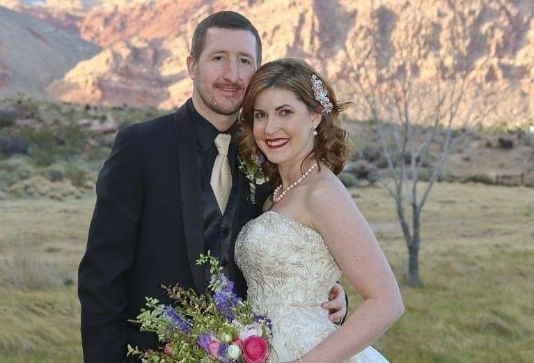 A bride and groom are posing for a picture in front of a mountain at Red Rock National Park