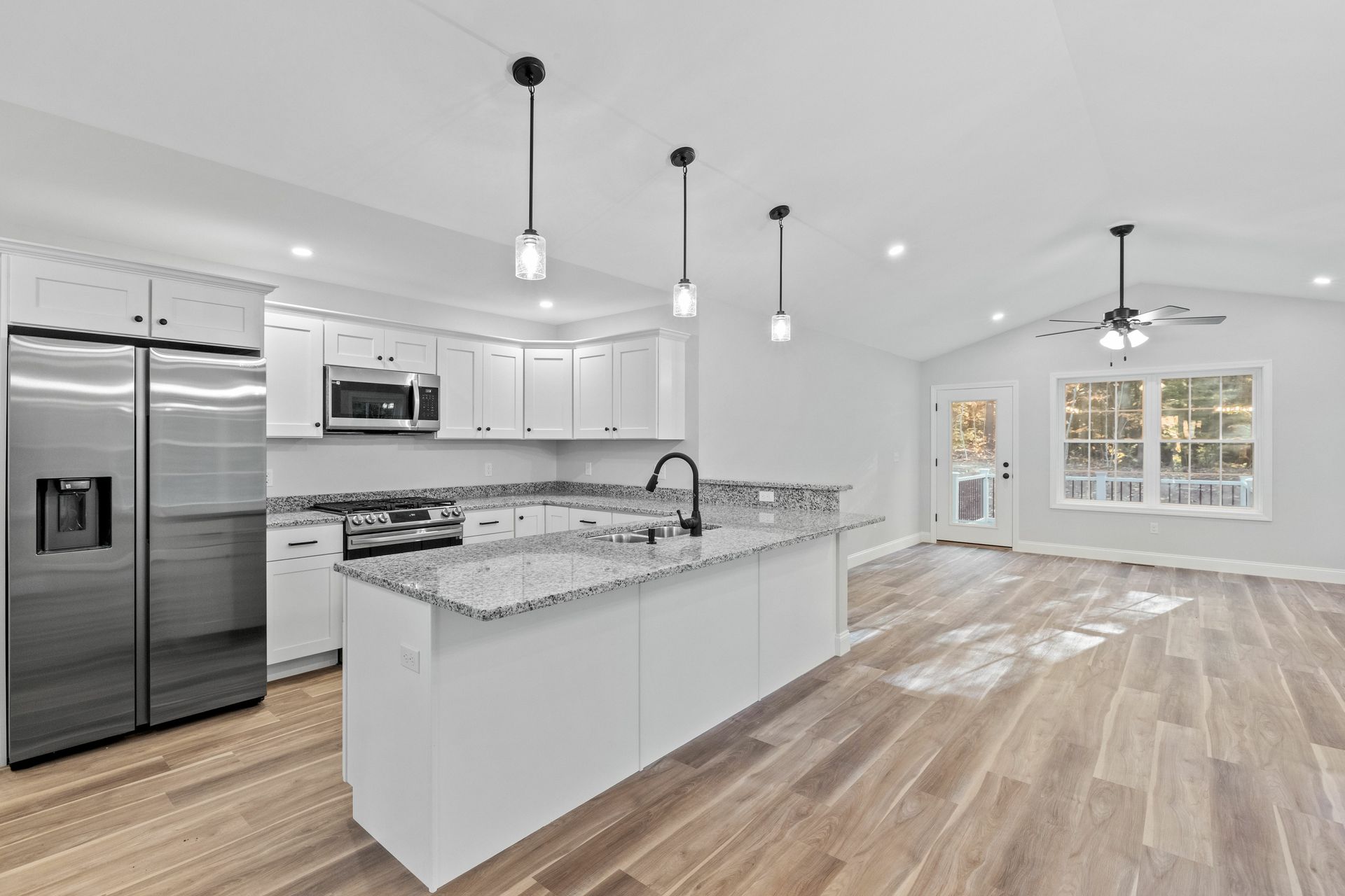 A kitchen with white cabinets , granite counter tops , stainless steel appliances and hardwood floors.