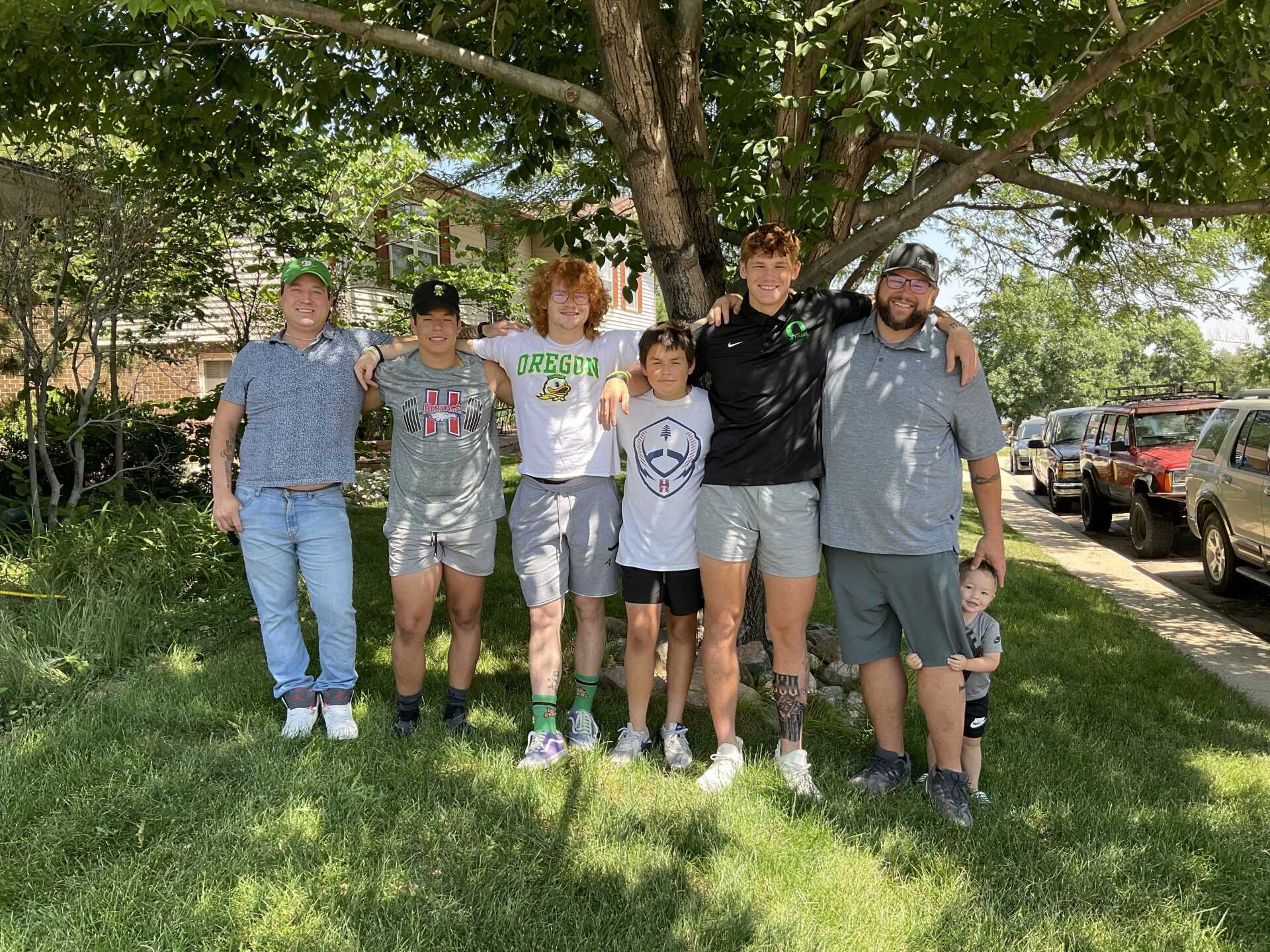 A group of people are posing for a picture in front of a tree.