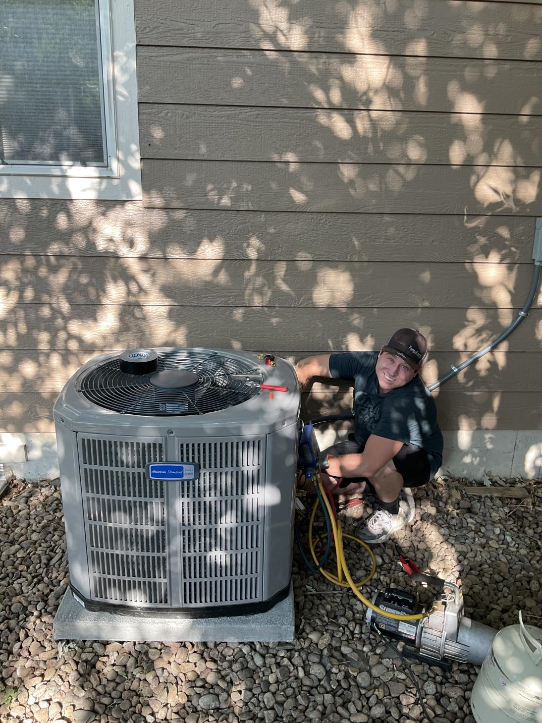 A man is working on an air conditioner outside of a house.