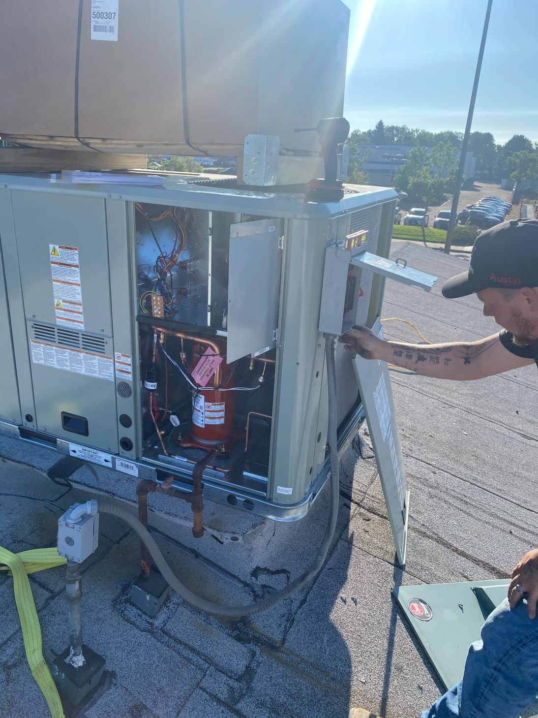 A man is working on an air conditioner on top of a roof.