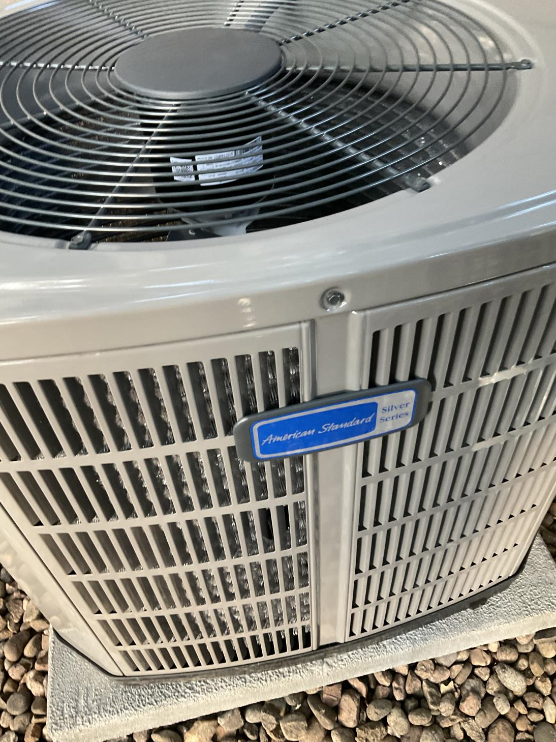 A white air conditioner is sitting on top of a pile of rocks.