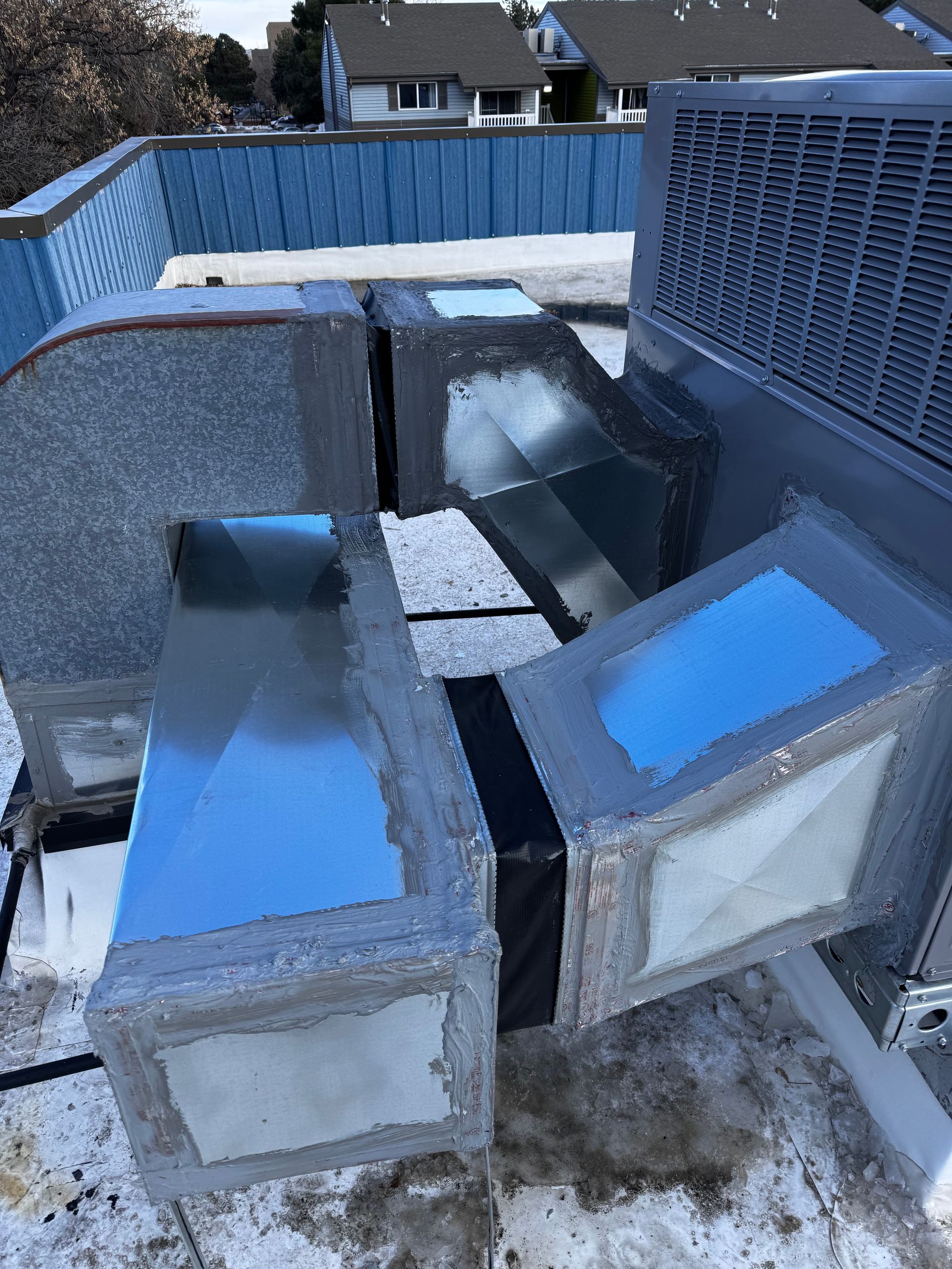 A bunch of ducts are sitting on top of a snow covered roof.