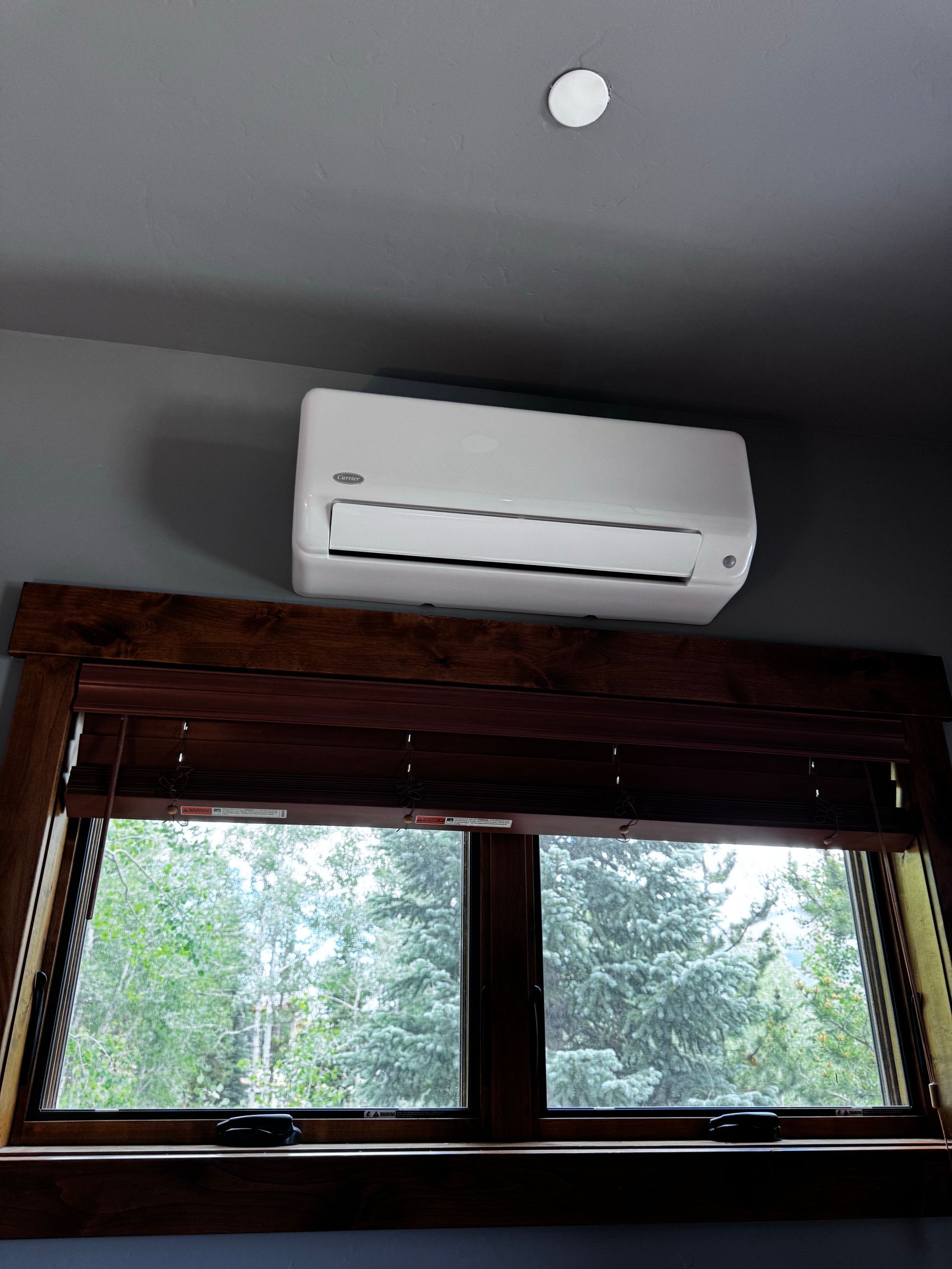 A man is kneeling down in front of a house looking at a tablet.