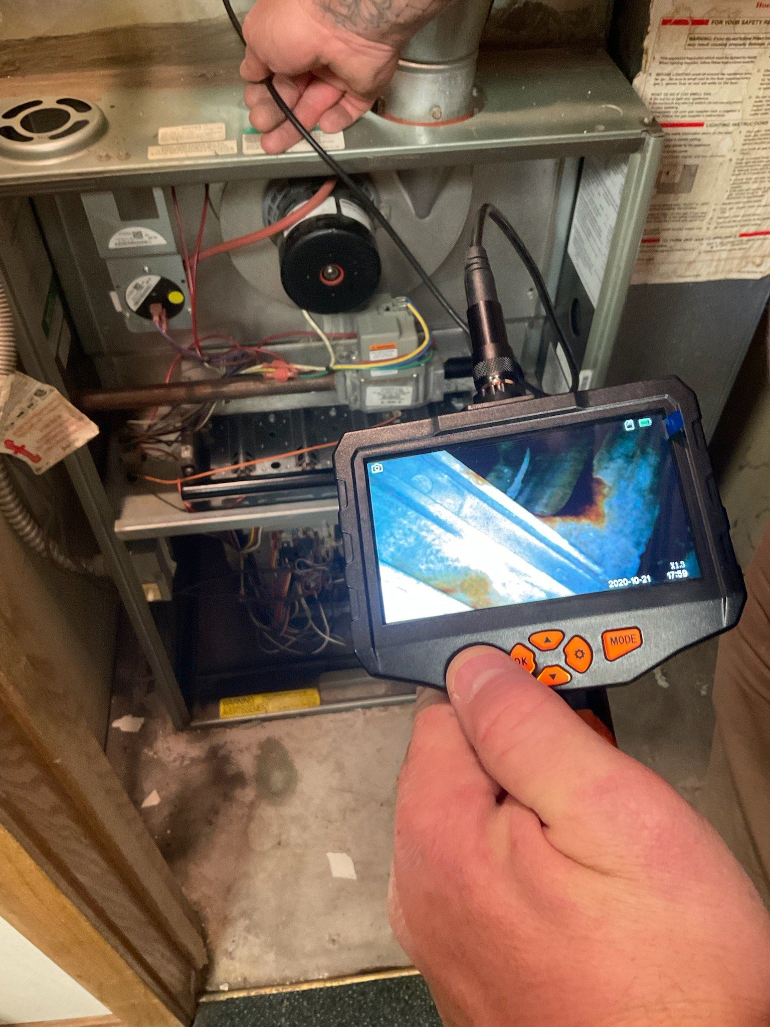 A person is holding a camera in front of a heater.