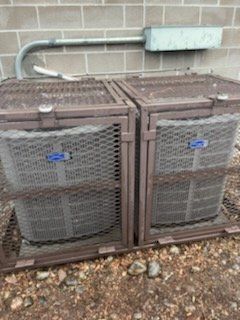 Two air conditioners are sitting next to each other in a cage.