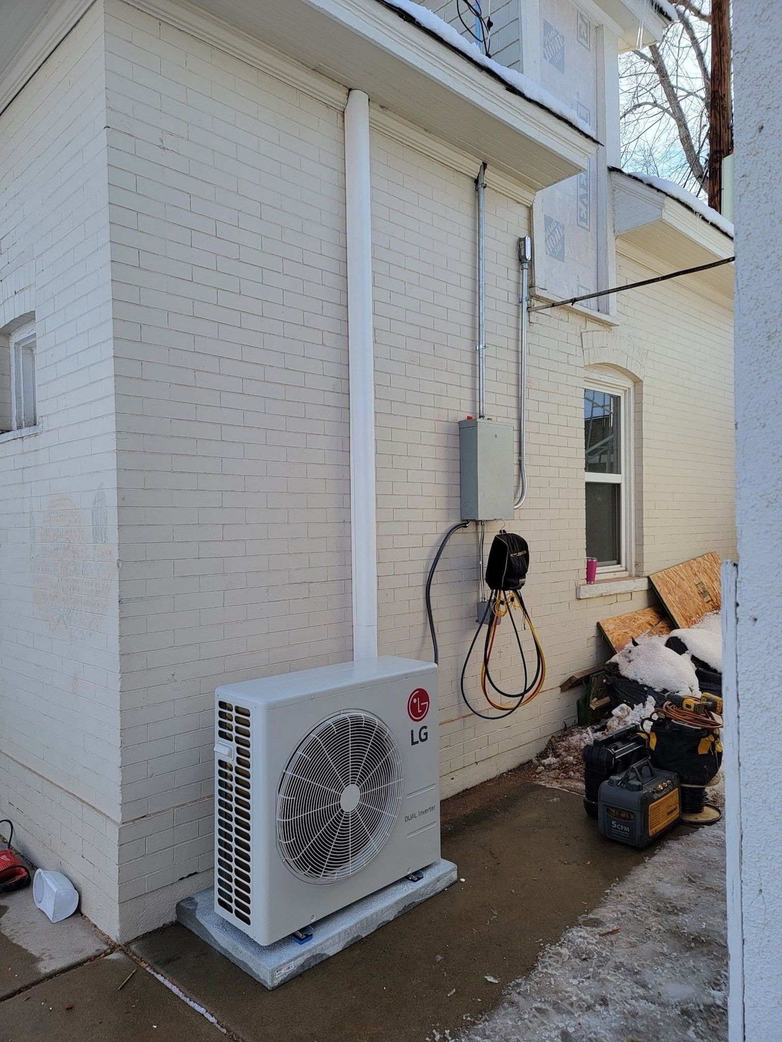 A white brick building with a white box on the side of it.