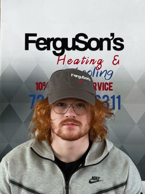 A man wearing a hat and glasses is standing in front of a sign for ferguson 's heating and cooling