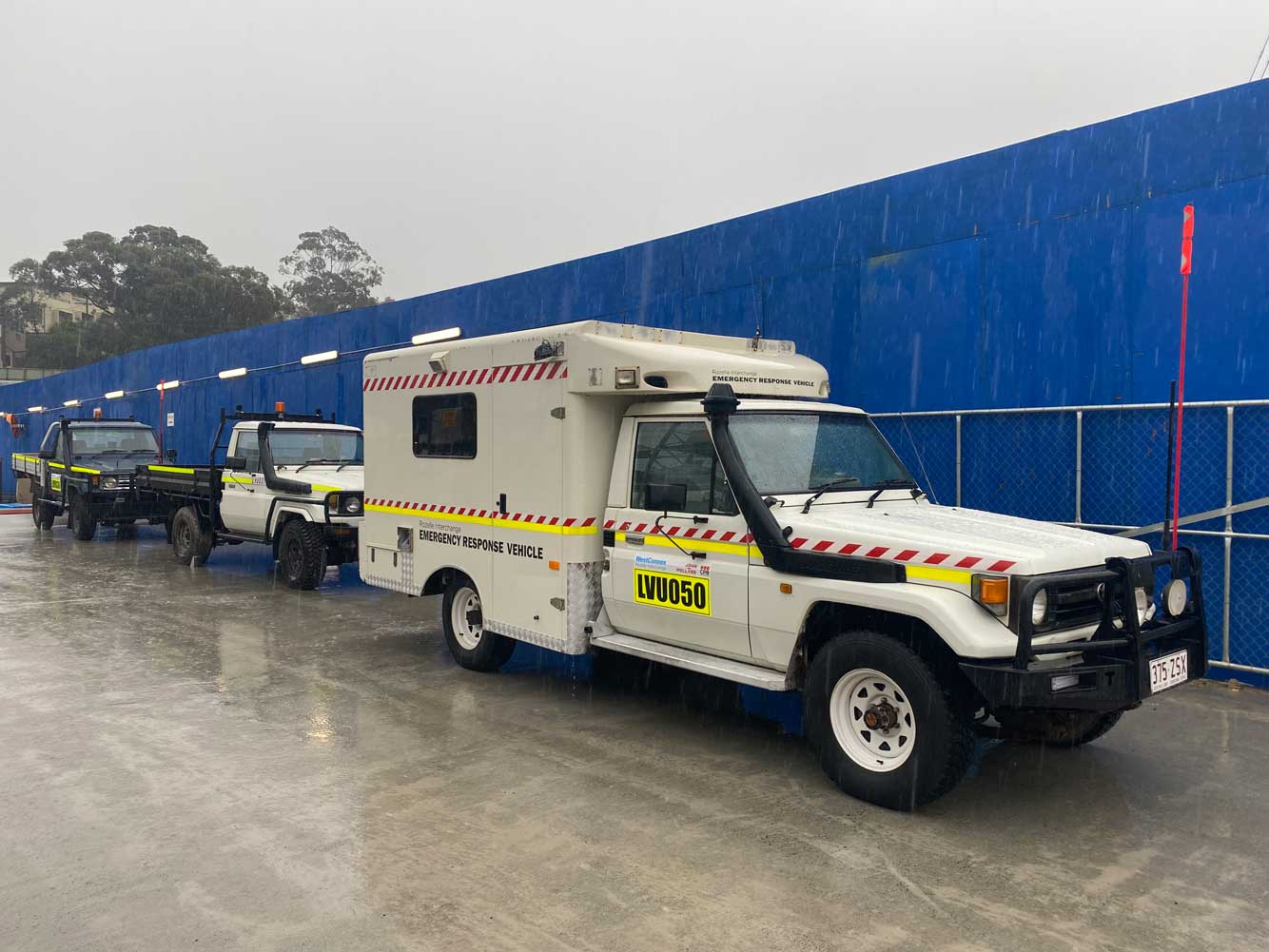 A white ambulance is parked in front of a blue wall.