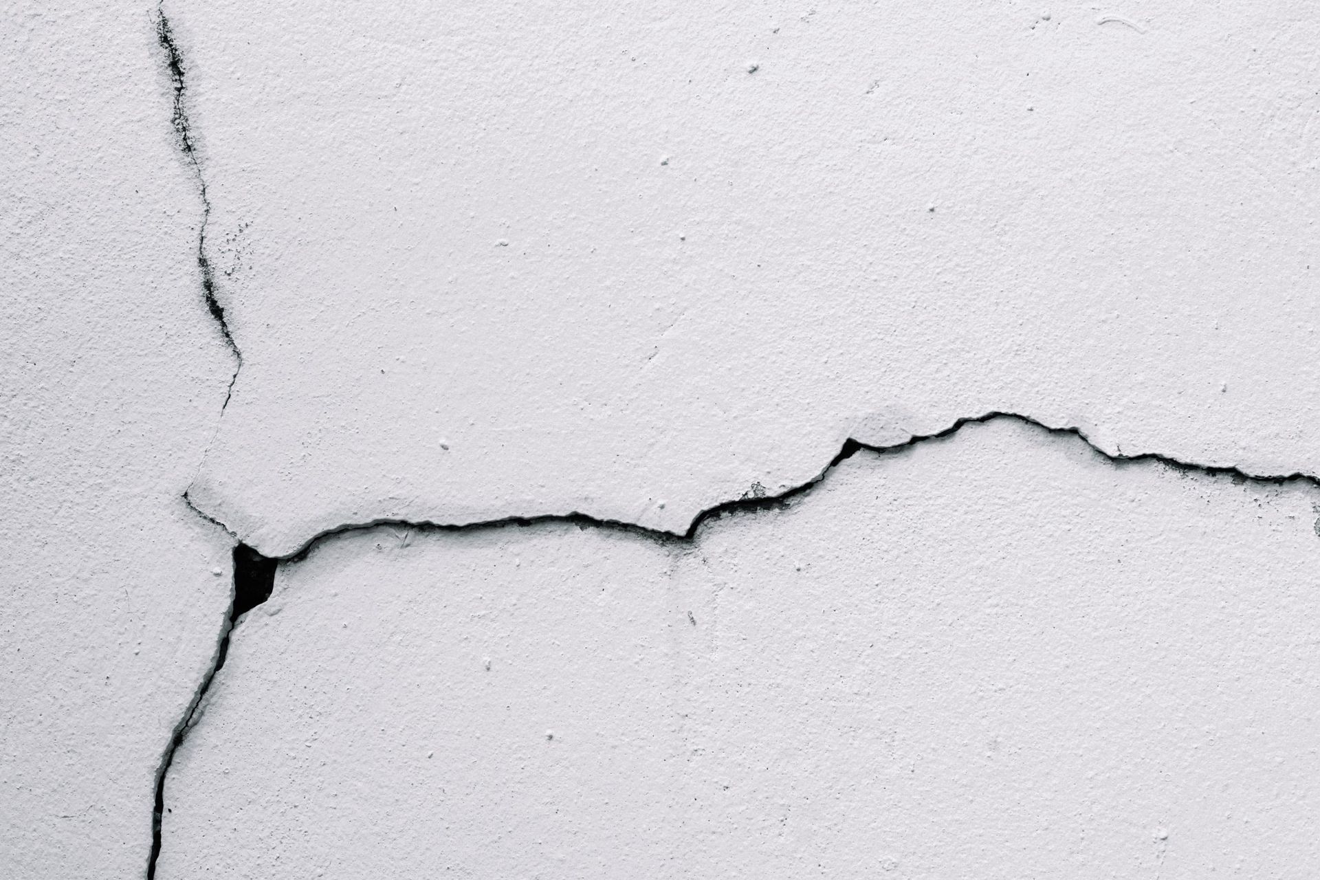 Cracked white wall with a black, jagged fissure running across it.