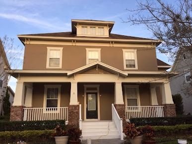 Two-story brown house with white trim, porch, and small front yard.
