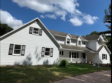 White house with black shutters against a blue sky.