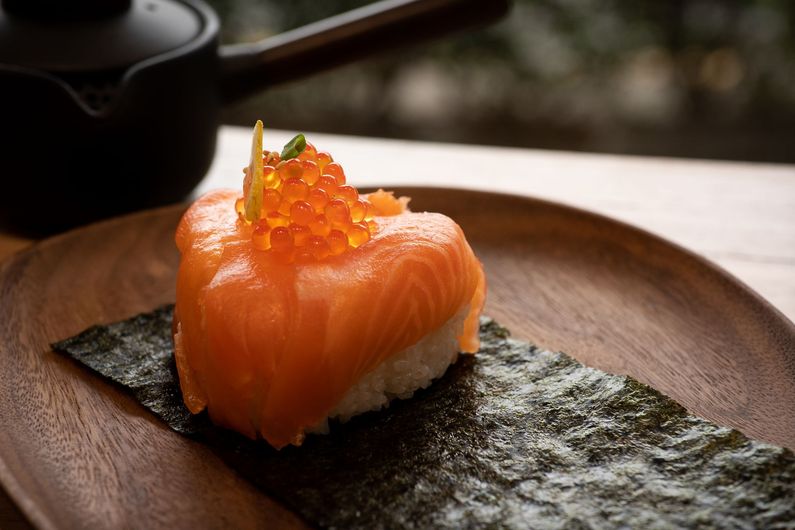 A piece of onigiri of seaweed on a wooden plate.