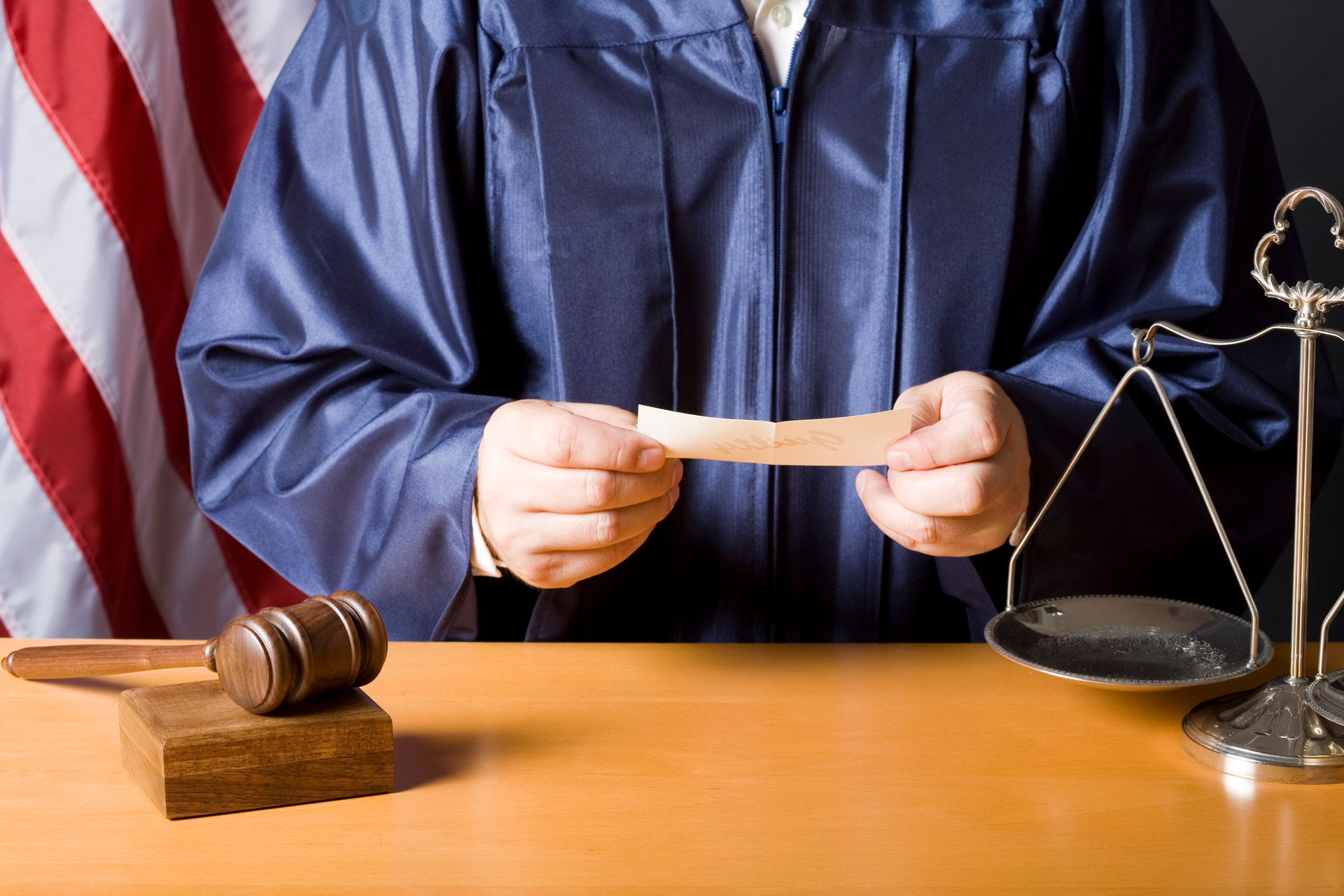 A judge in a blue robe is holding a piece of paper