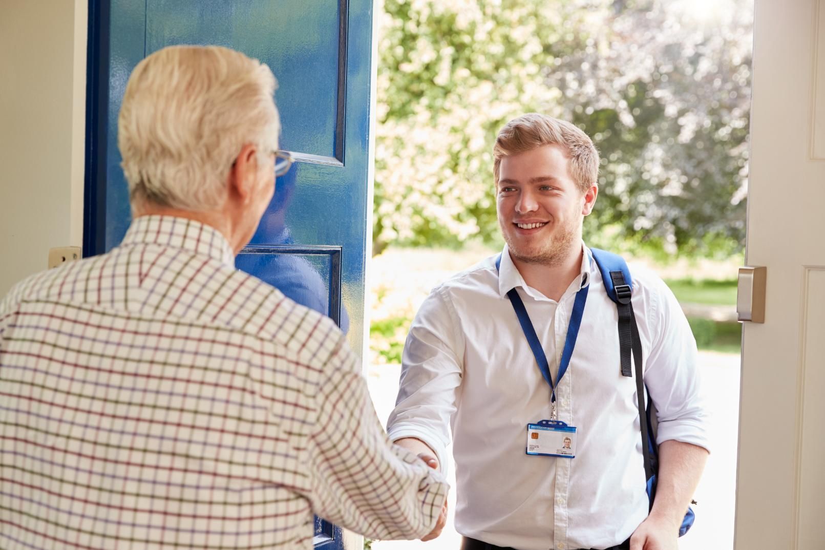 Man shakes hands with older person at a doorway, smiling.