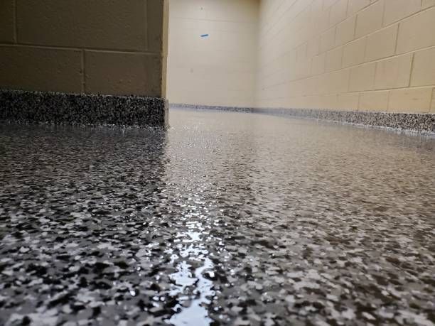 A close up of a concrete floor with a brick wall in the background.