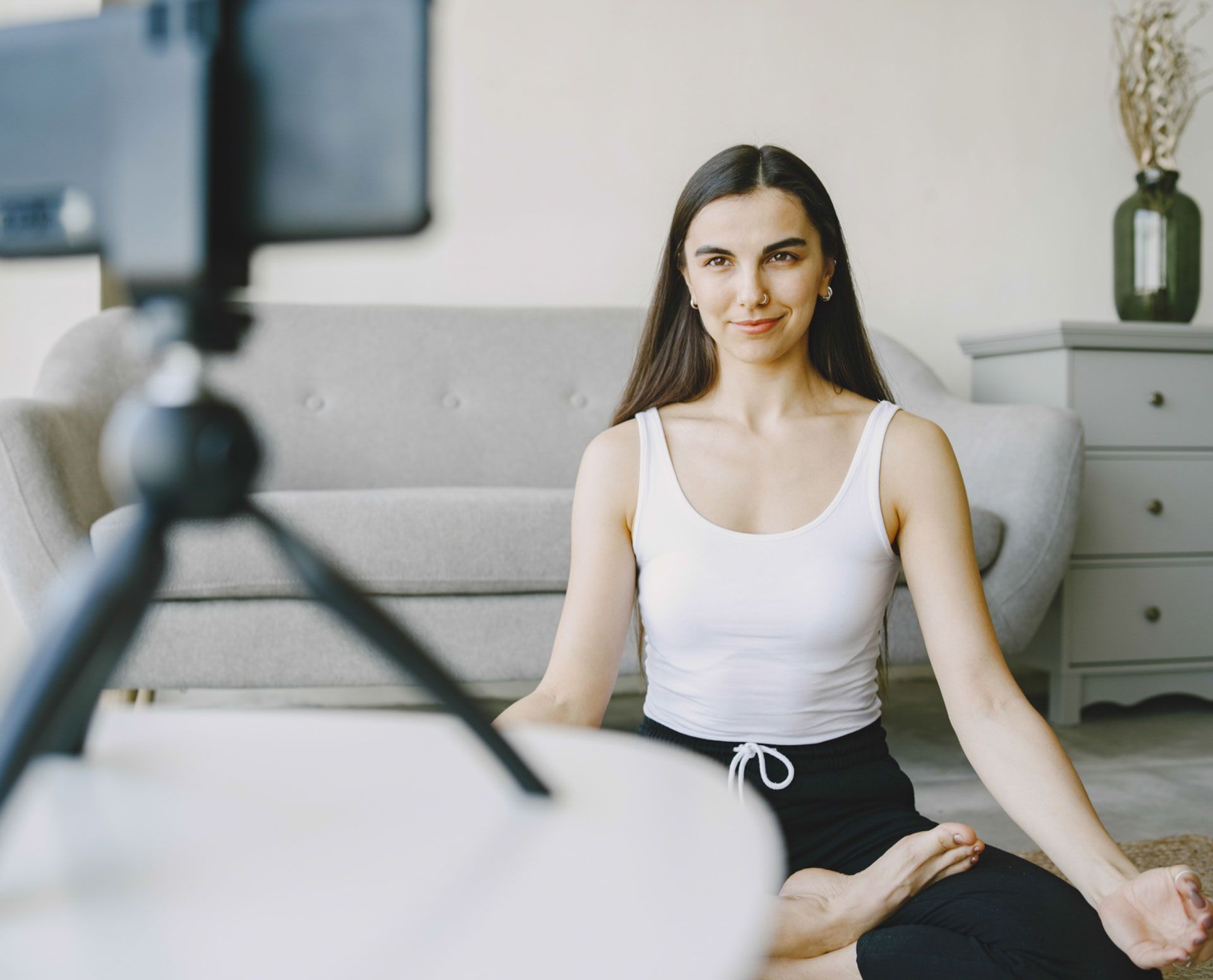 A woman is sitting in a lotus position in front of a camera.