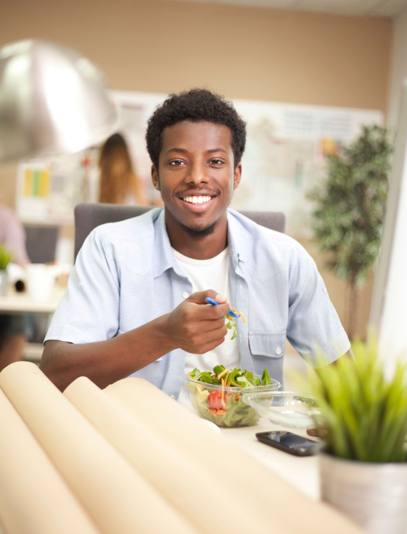 A man is sitting at a table eating a salad.