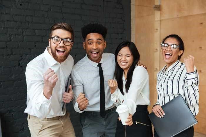 A group of business people are standing next to each other and celebrating.