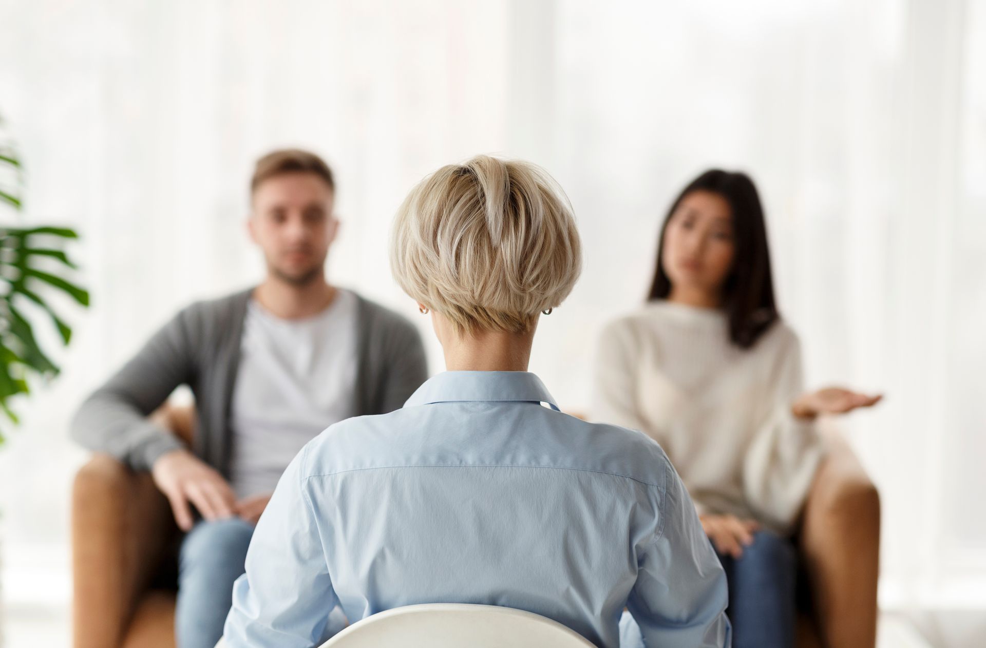 A woman is sitting in a chair talking to a man and a woman.