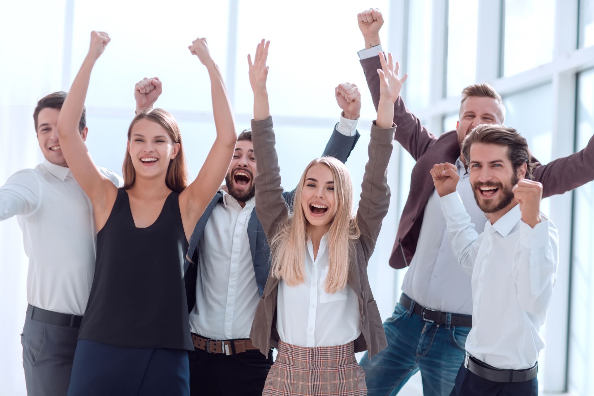 A group of people are standing next to each other with their arms in the air.