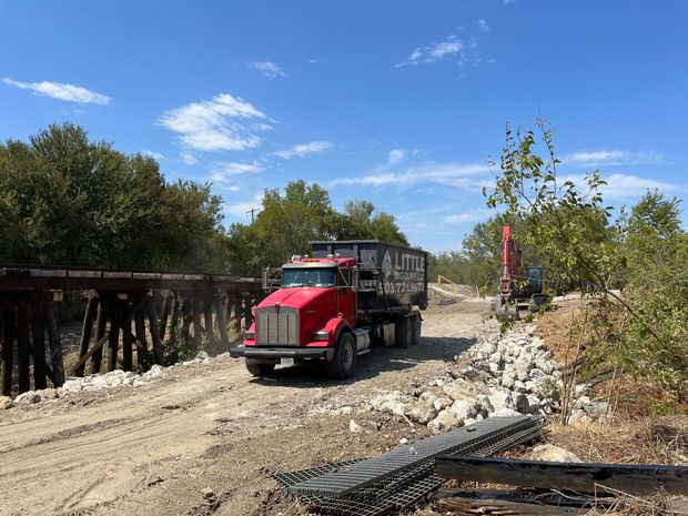A red truck is driving down a dirt road.
