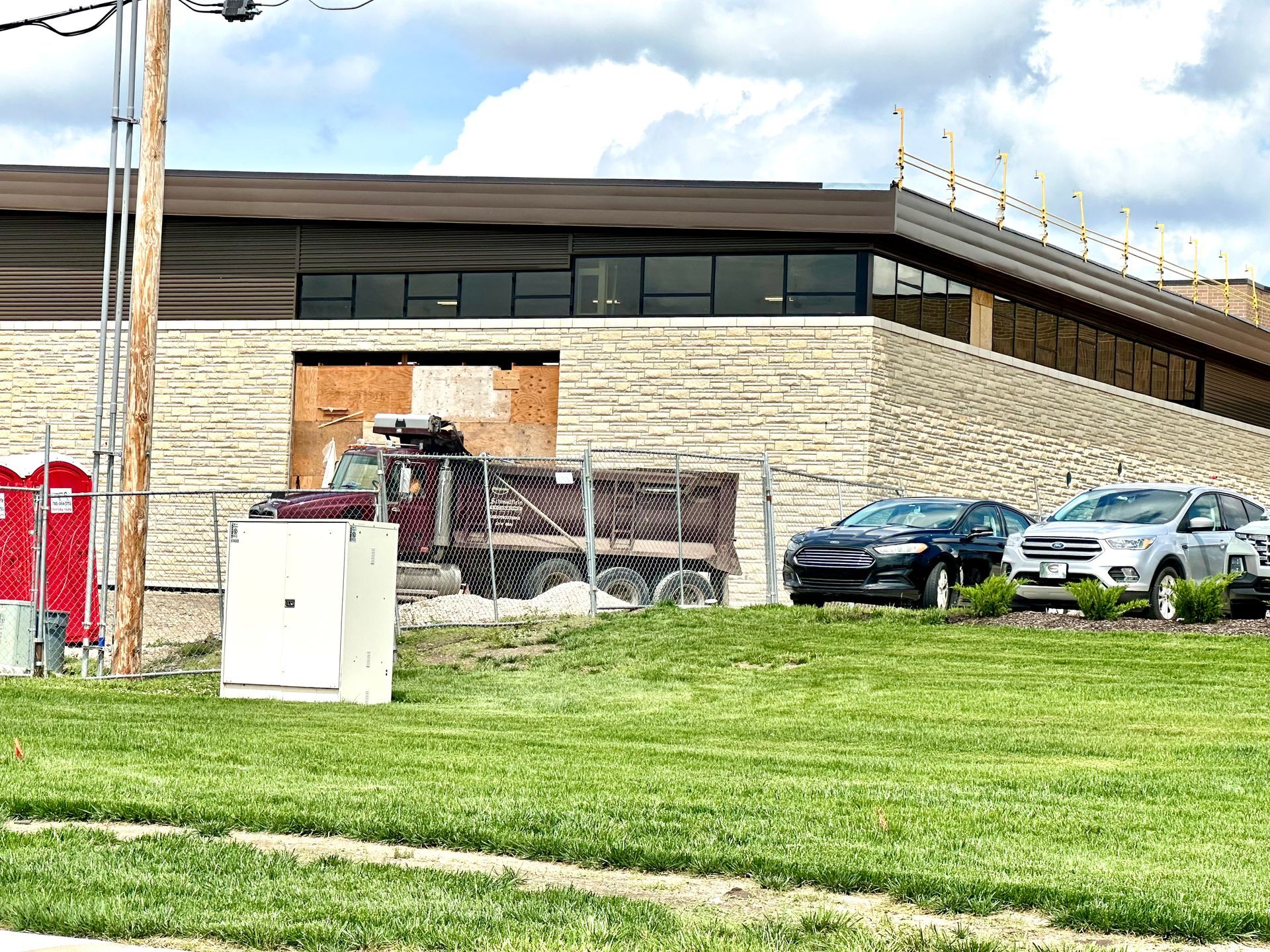 A dump truck is parked in front of a building under construction.