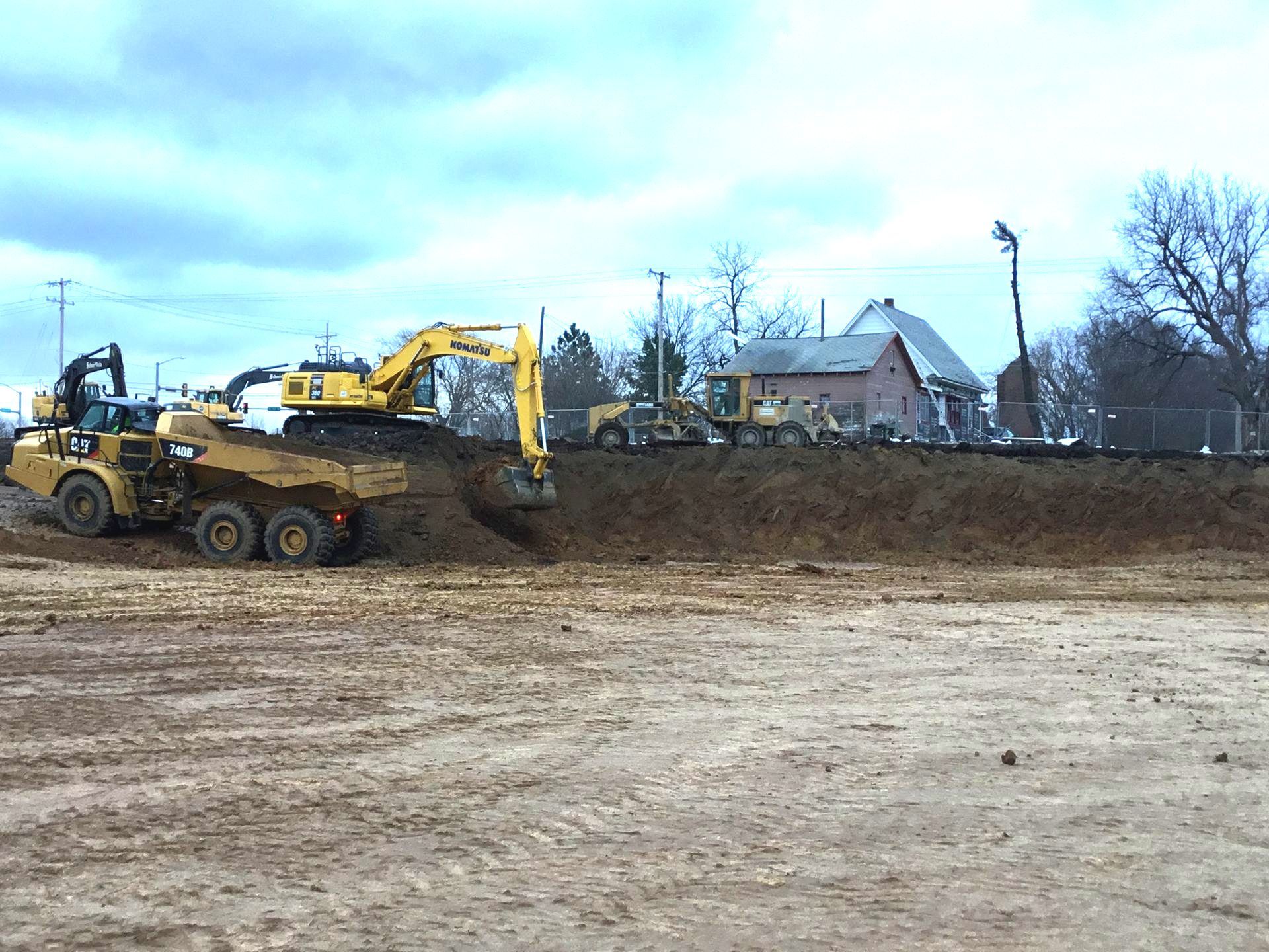 A dump truck is being loaded with dirt by a yellow excavator