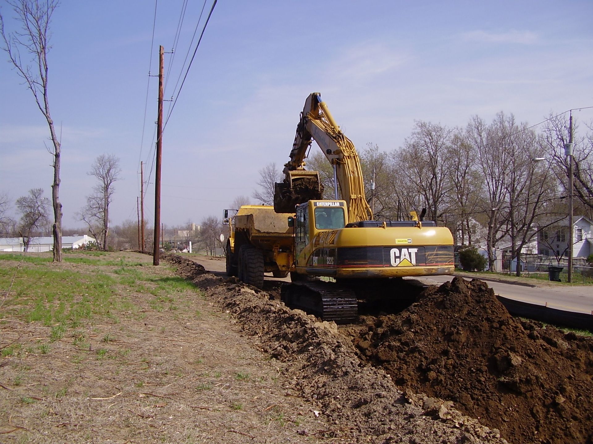 A cat excavator is digging a hole in a field