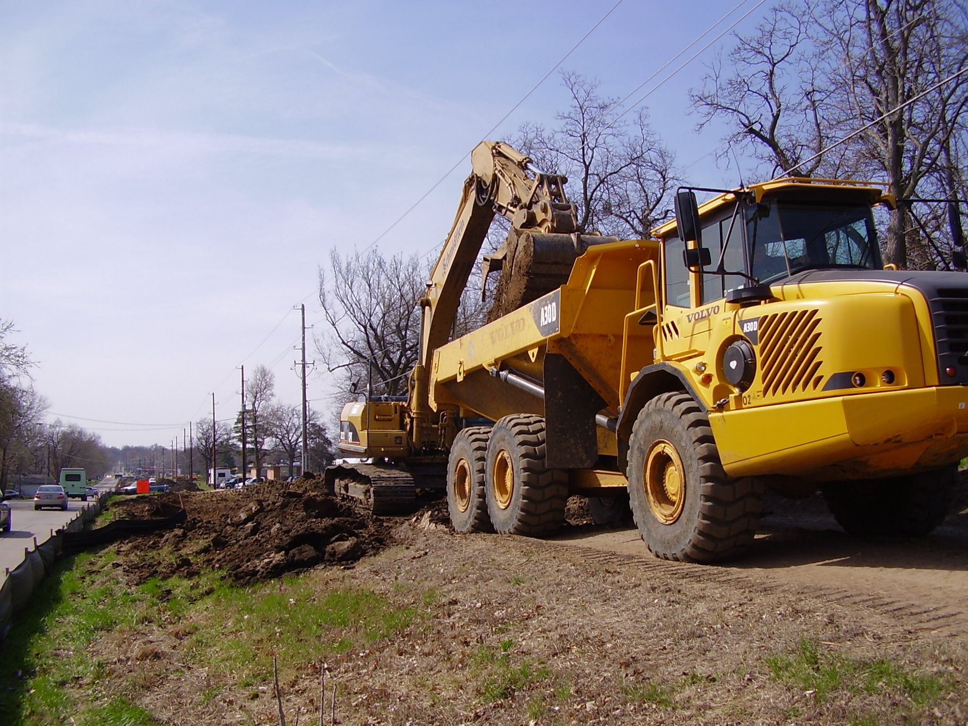 A yellow dump truck is parked next to an excavator