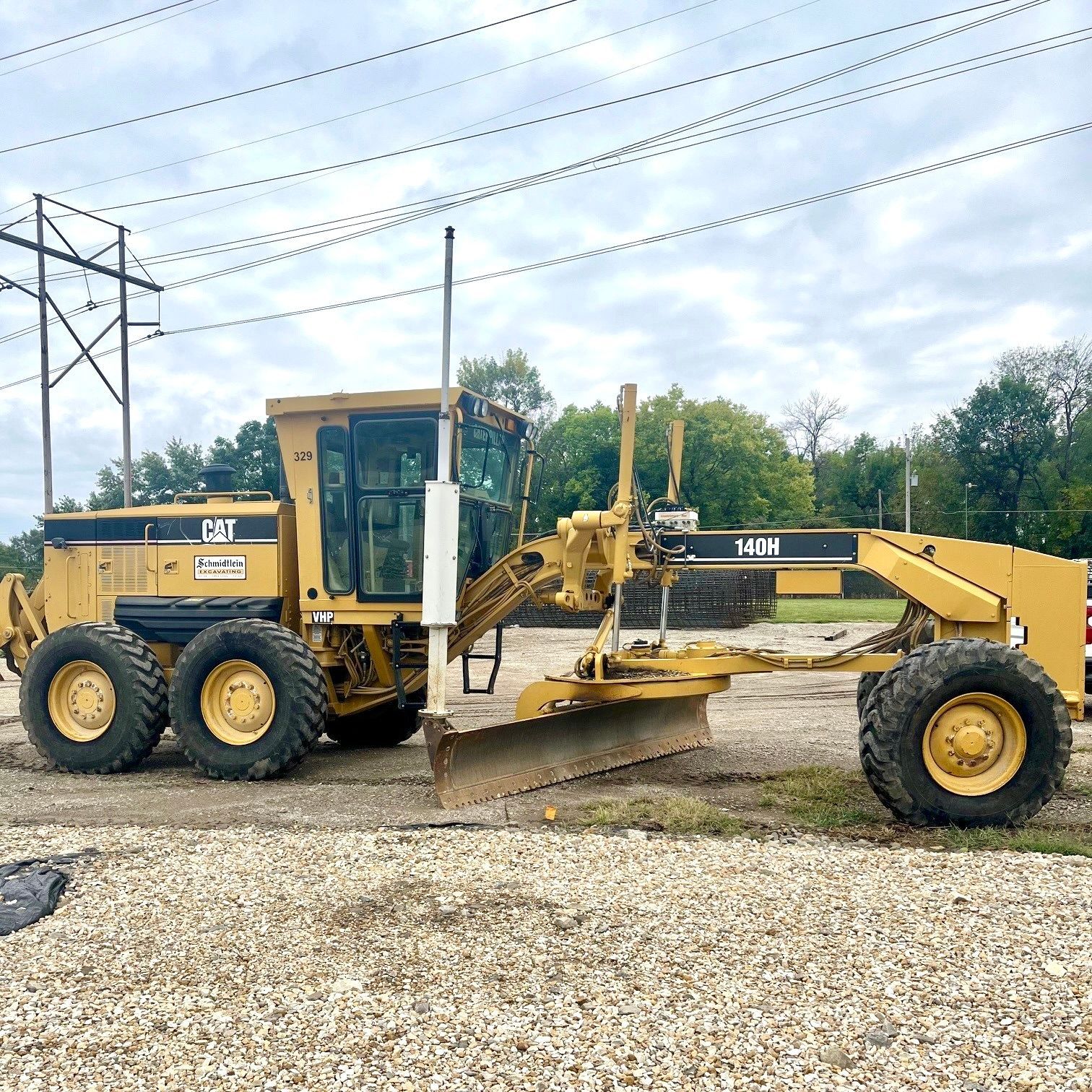 A yellow komatsu tractor is parked on a dirt road
