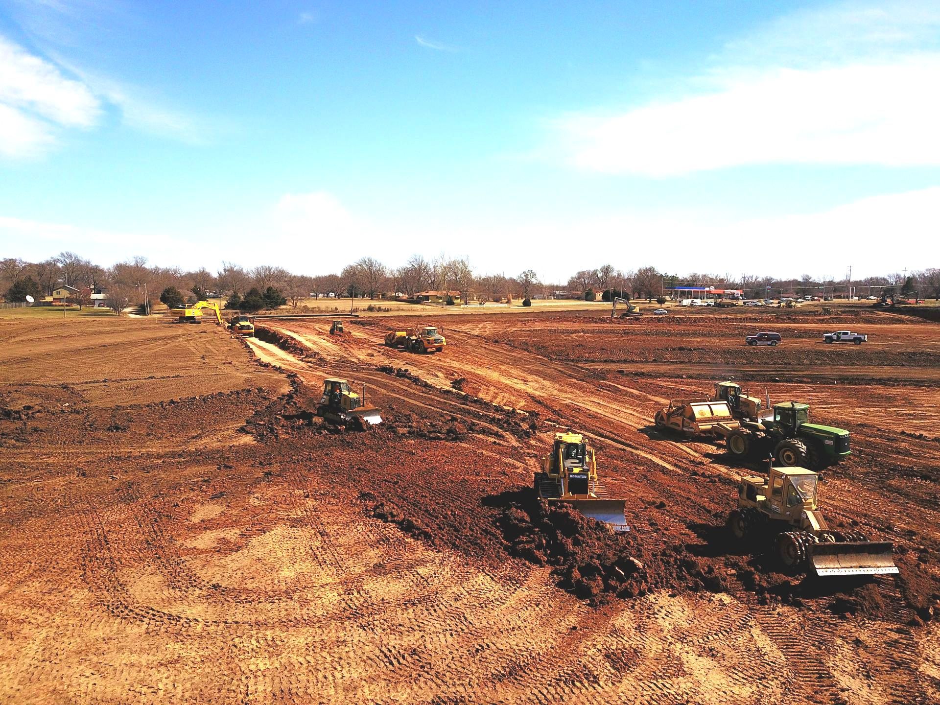 A group of tractors are working on a dirt field.