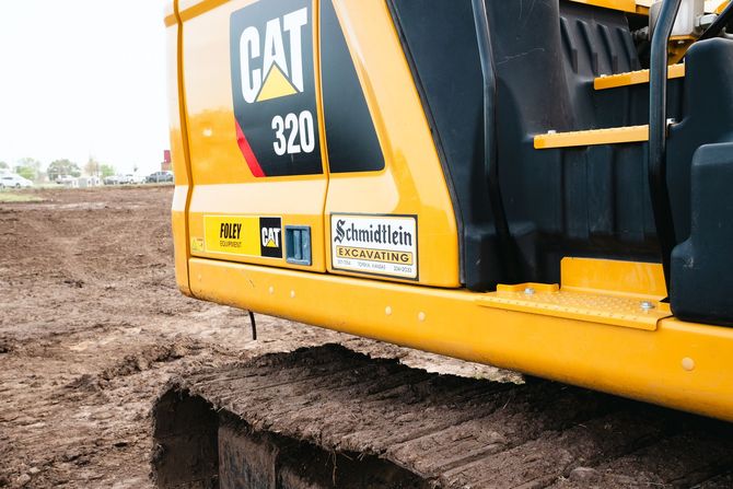 A yellow cat 320 excavator is parked in a dirt field