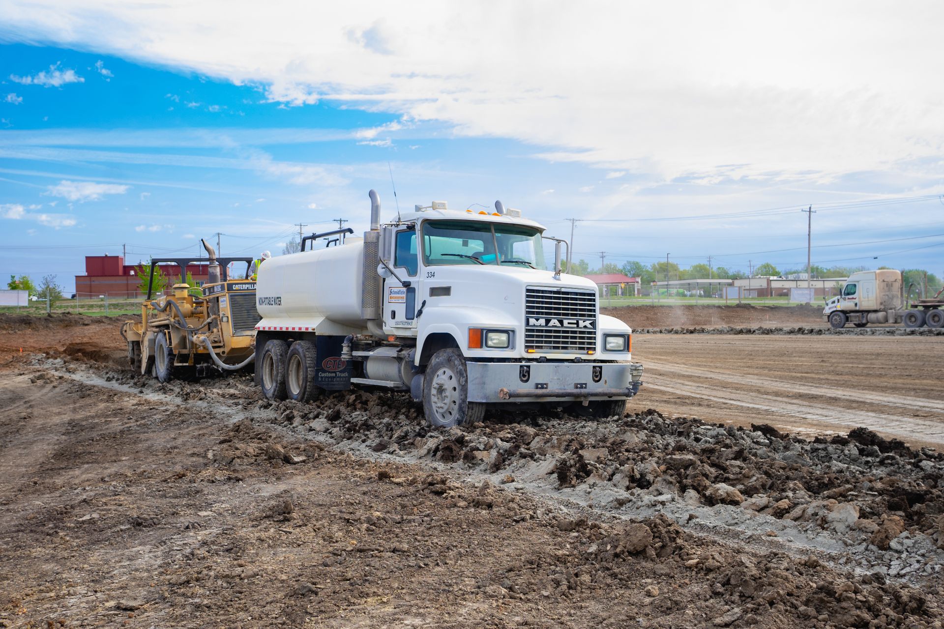 A white truck is driving through a muddy field.