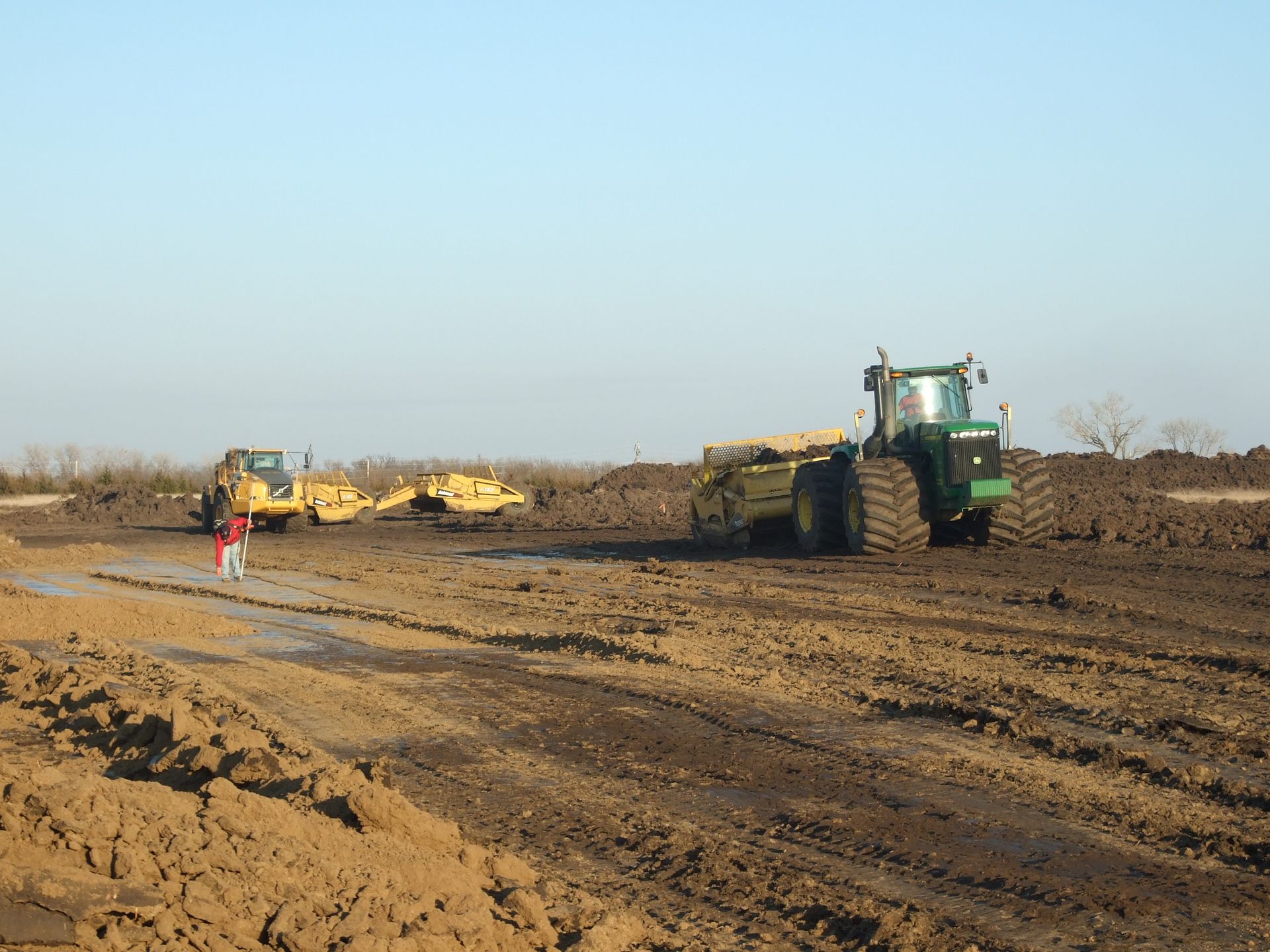 A green john deere tractor is driving through a dirt field