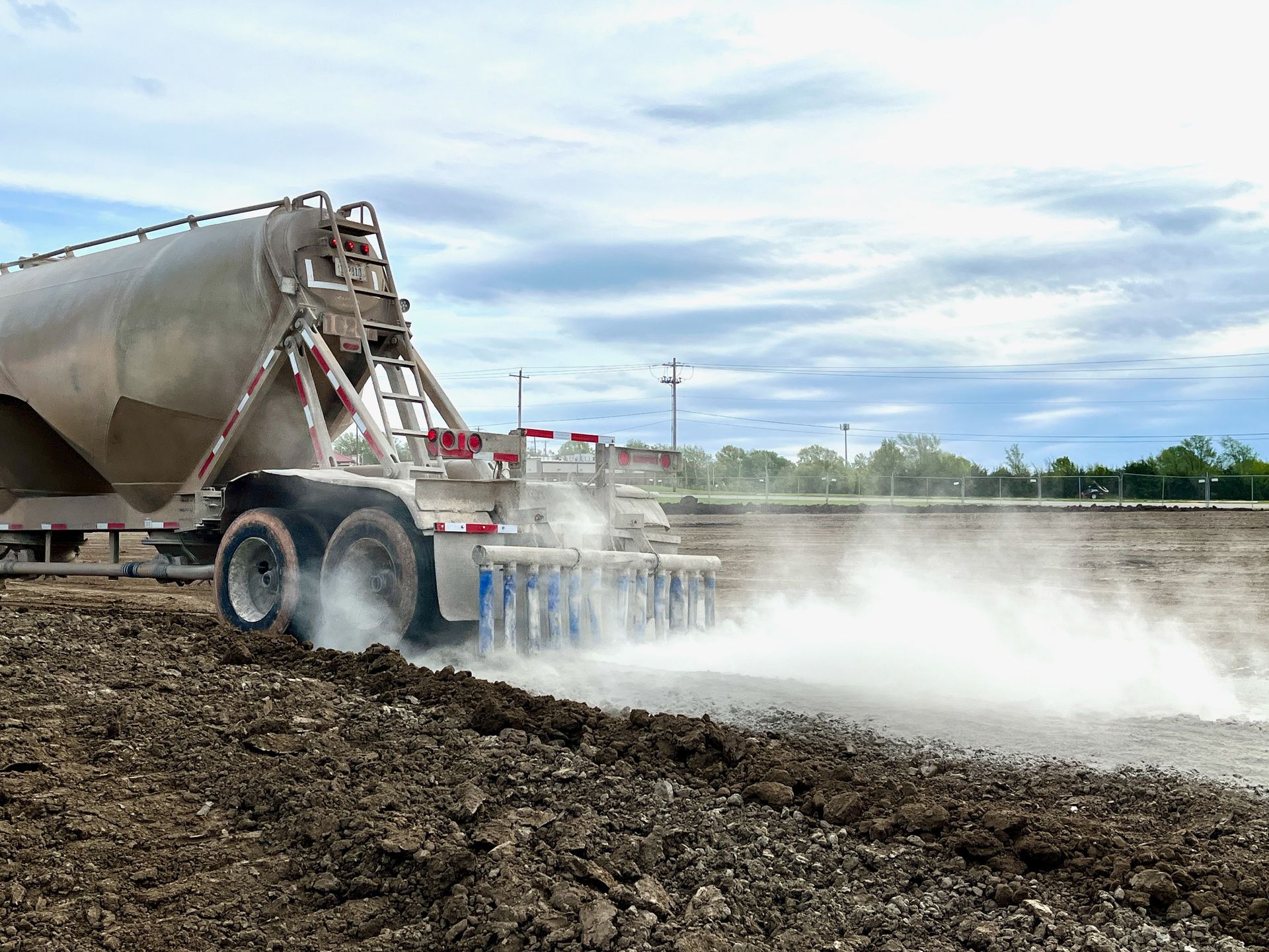 A truck is spreading fertilizer on a dirt field.