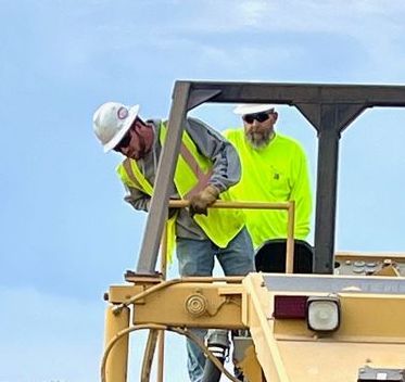 Two construction workers are working on a bulldozer.