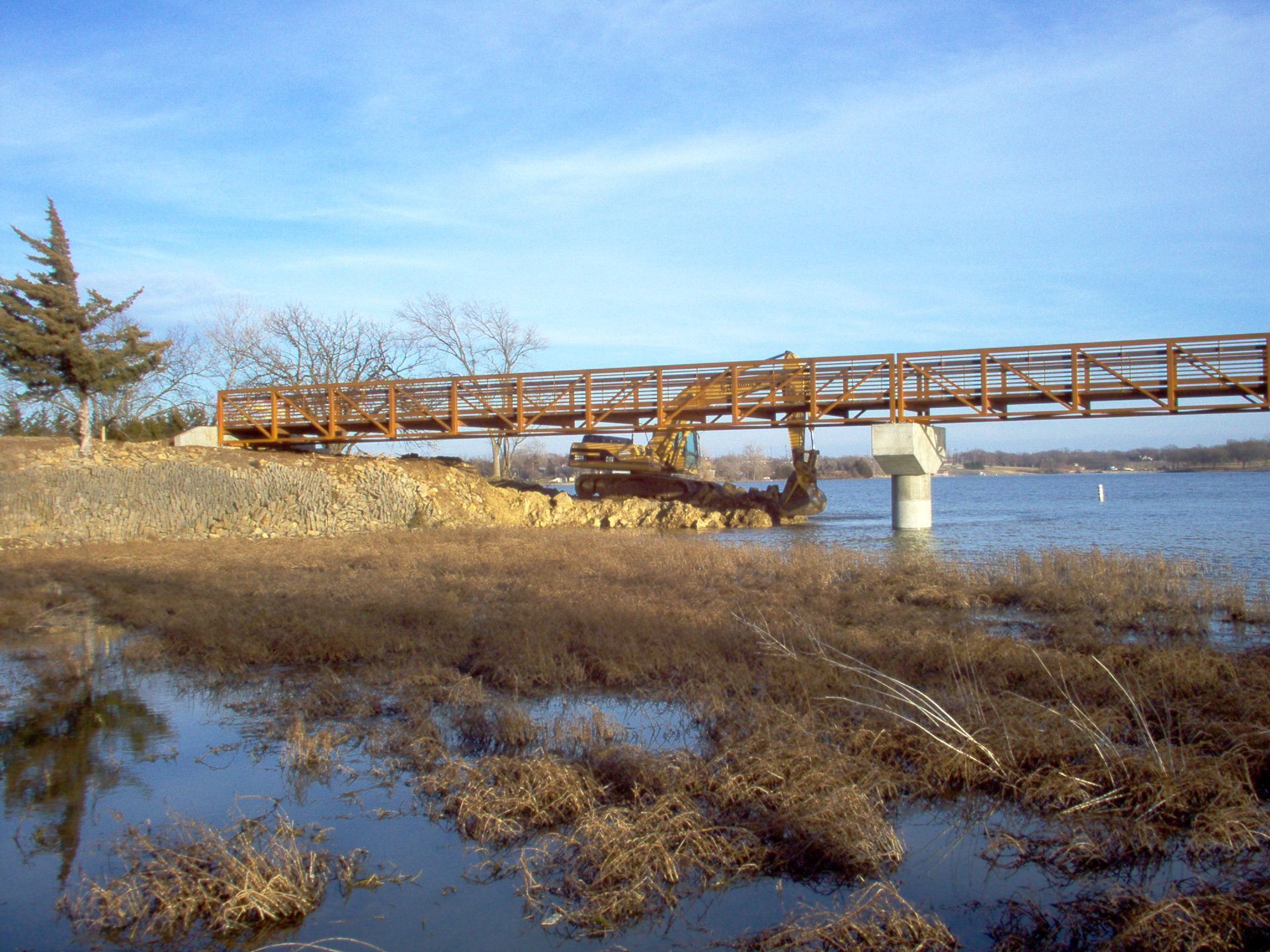 A bridge over a body of water with a tree in the background