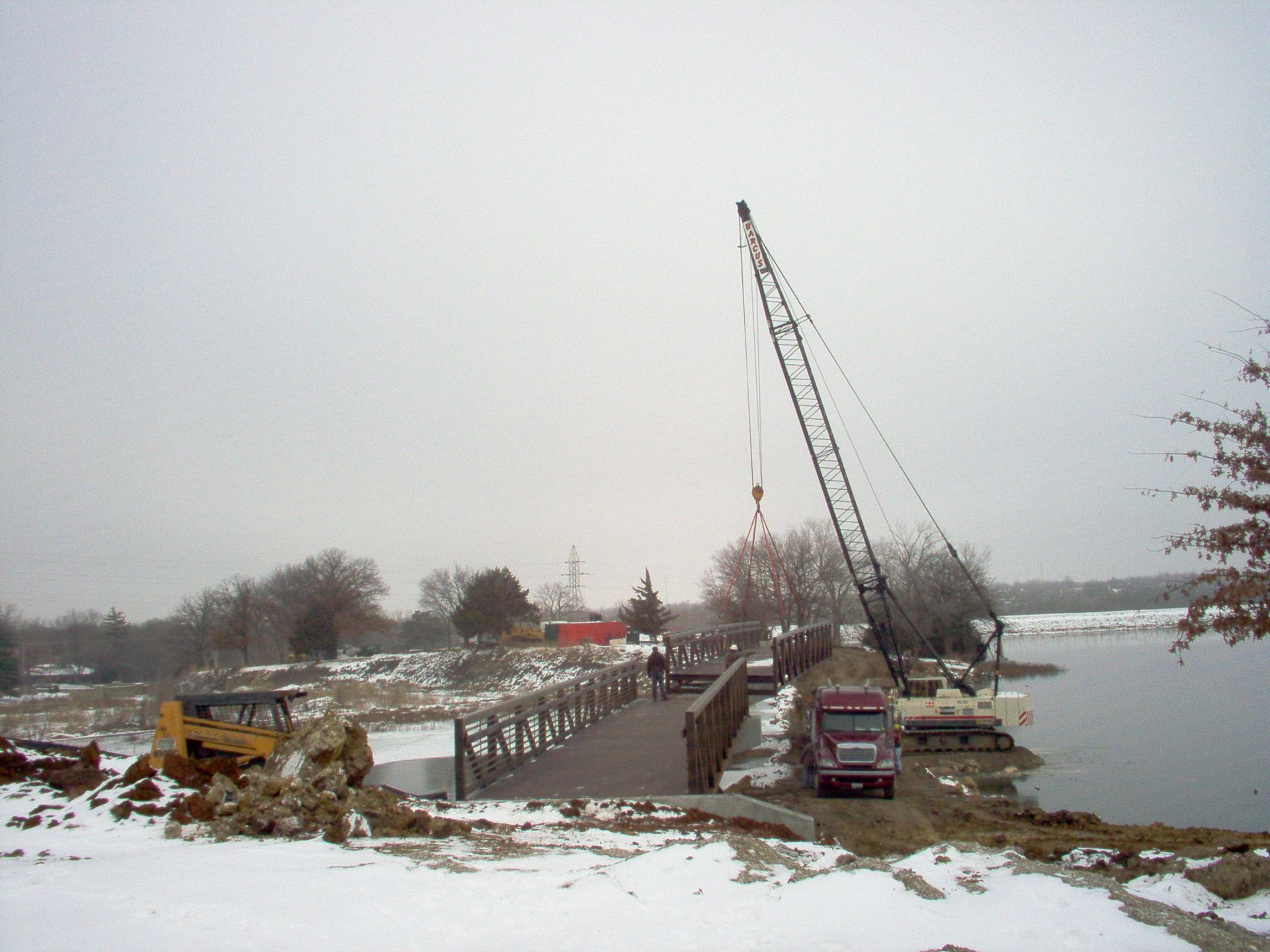 A large crane is lifting a bridge over a body of water