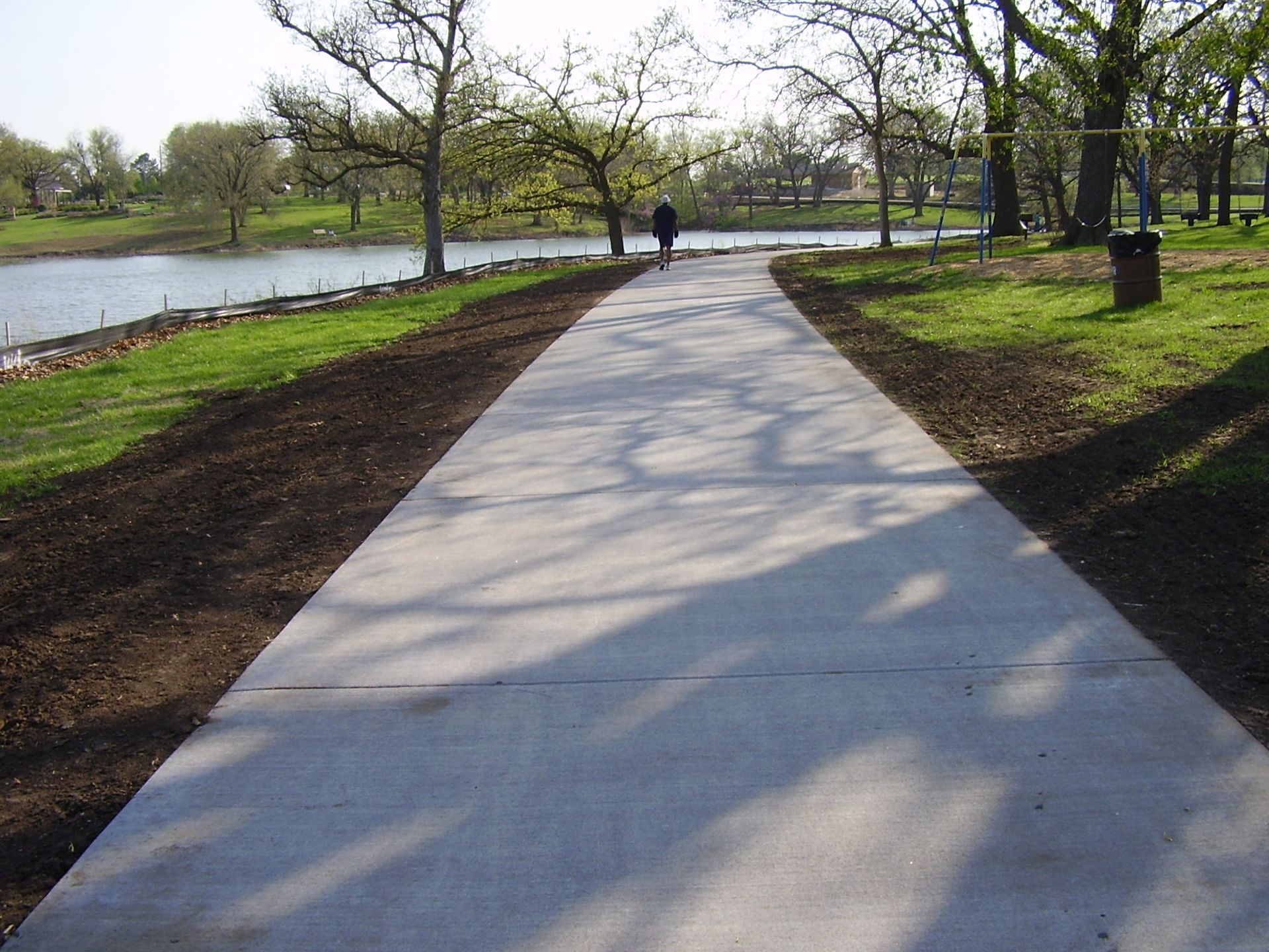 A person walking down a concrete path in a park