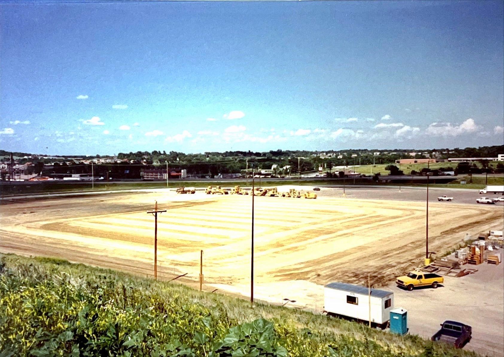 A large dirt field with a few cars parked in it