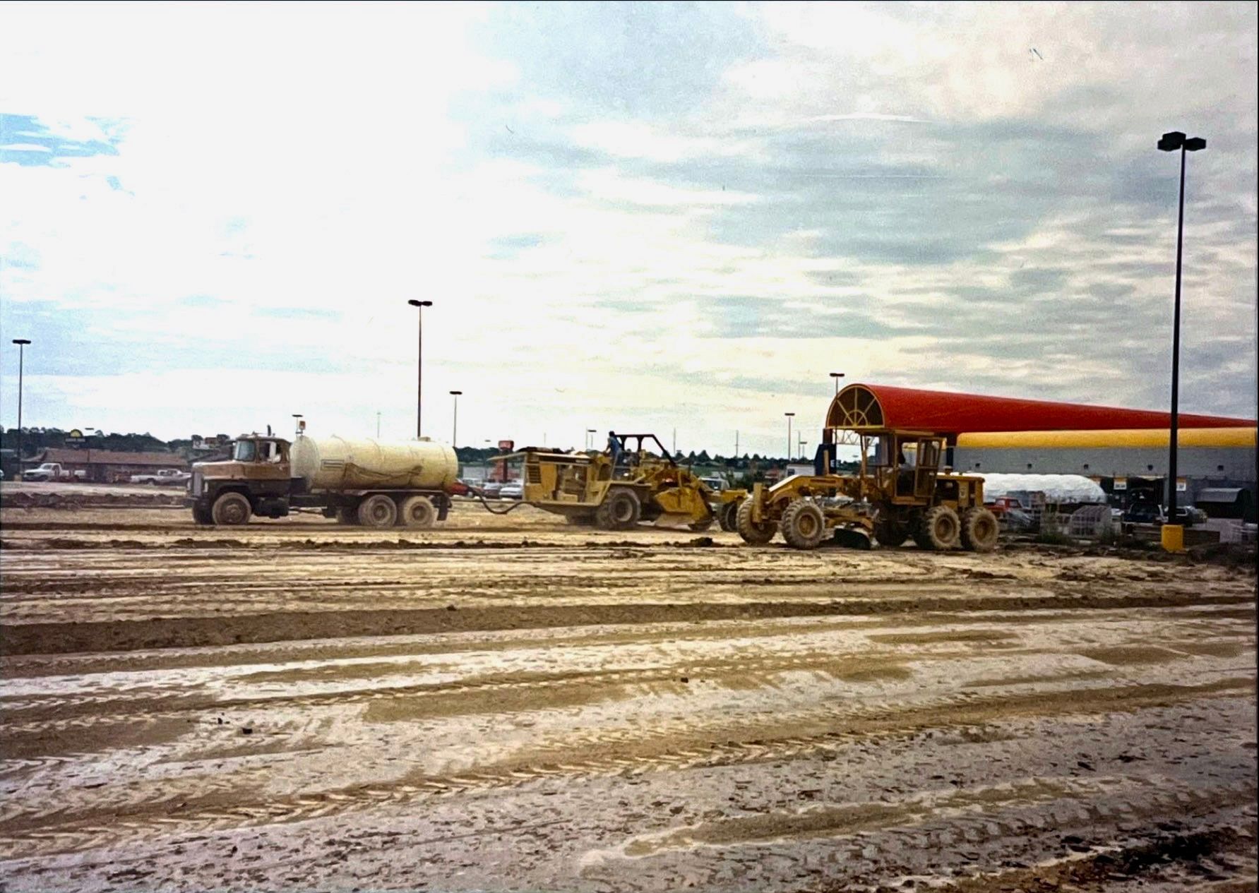 A muddy field with a tanker truck and a bulldozer