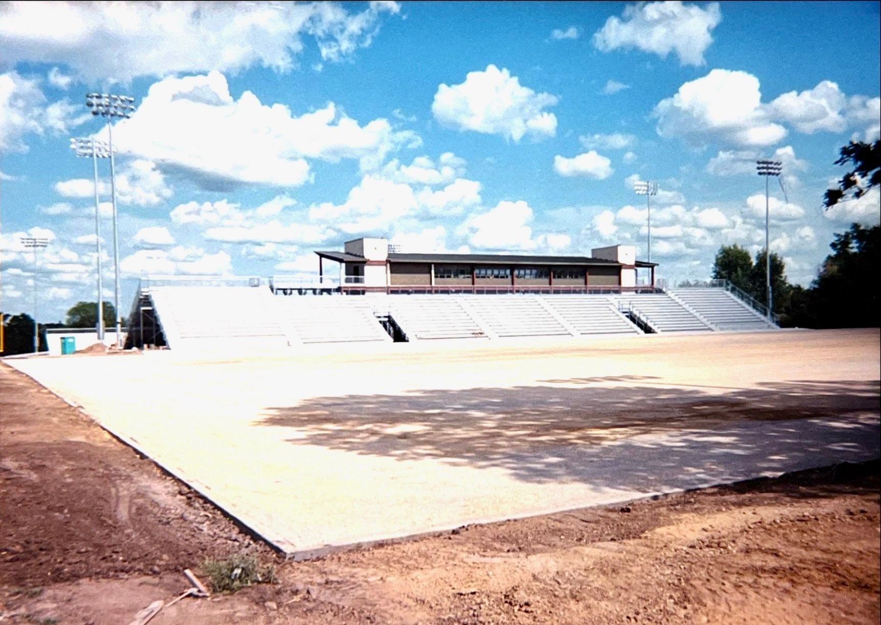 An empty stadium with a blue sky and clouds in the background