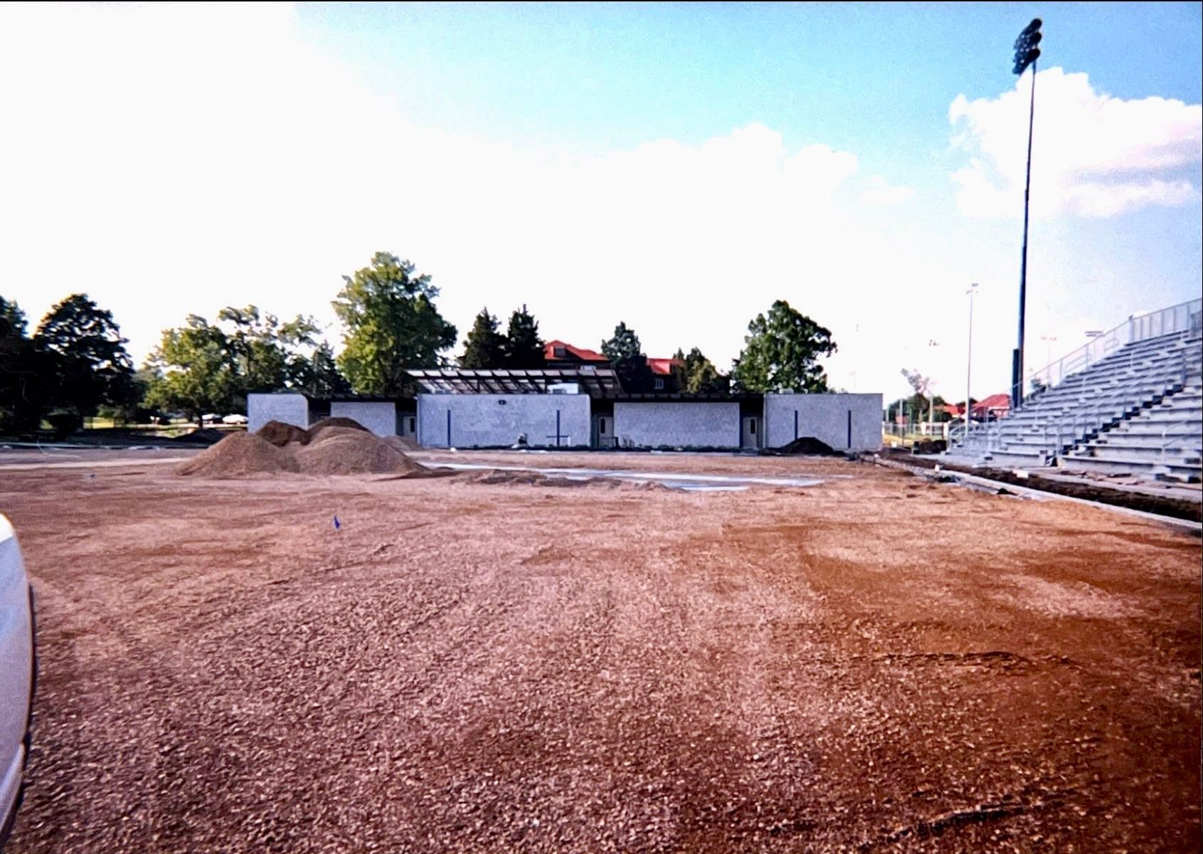 A dirt field with a stadium in the background