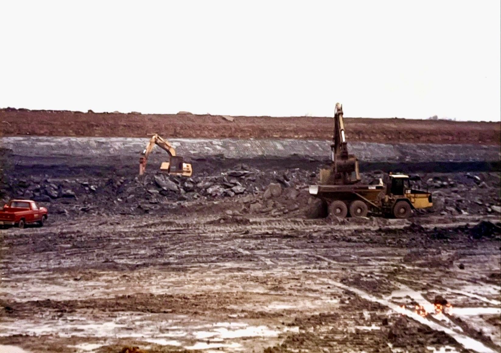 A red truck is parked in the middle of a muddy field.